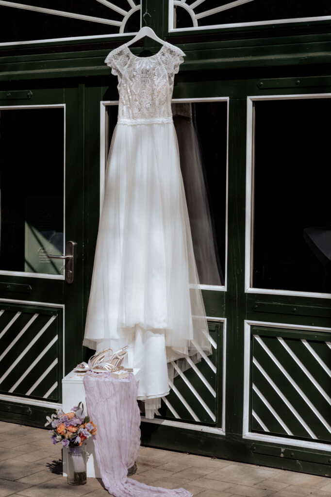 Hochzeitskleid hängt vor grüner Tür