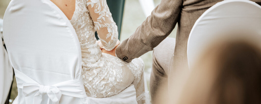 Hochzeitspaar Händchen haltend, sitzend