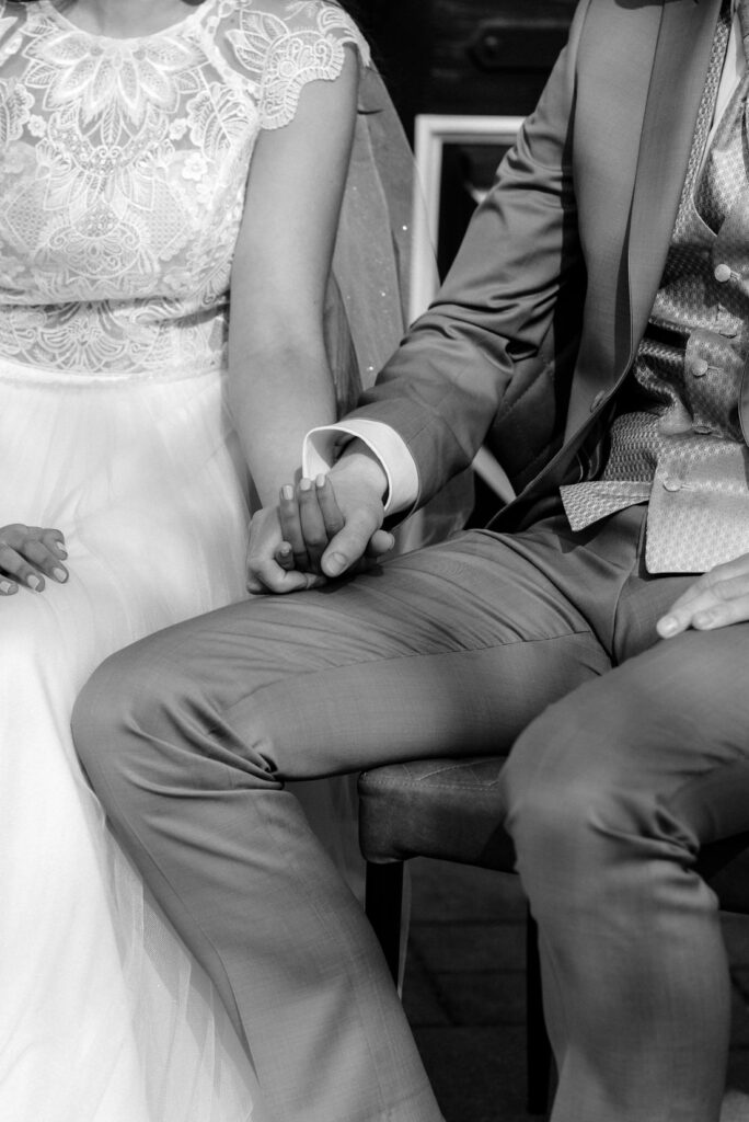 Hochzeitspaar hält Händchen, sitzt, schwarz-weiß Foto