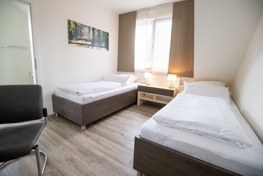 Modernes Doppelzimmer mit zwei Betten und hellem Holzboden